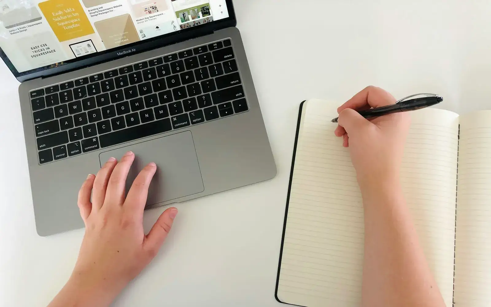 A person taking notes while working on a laptop