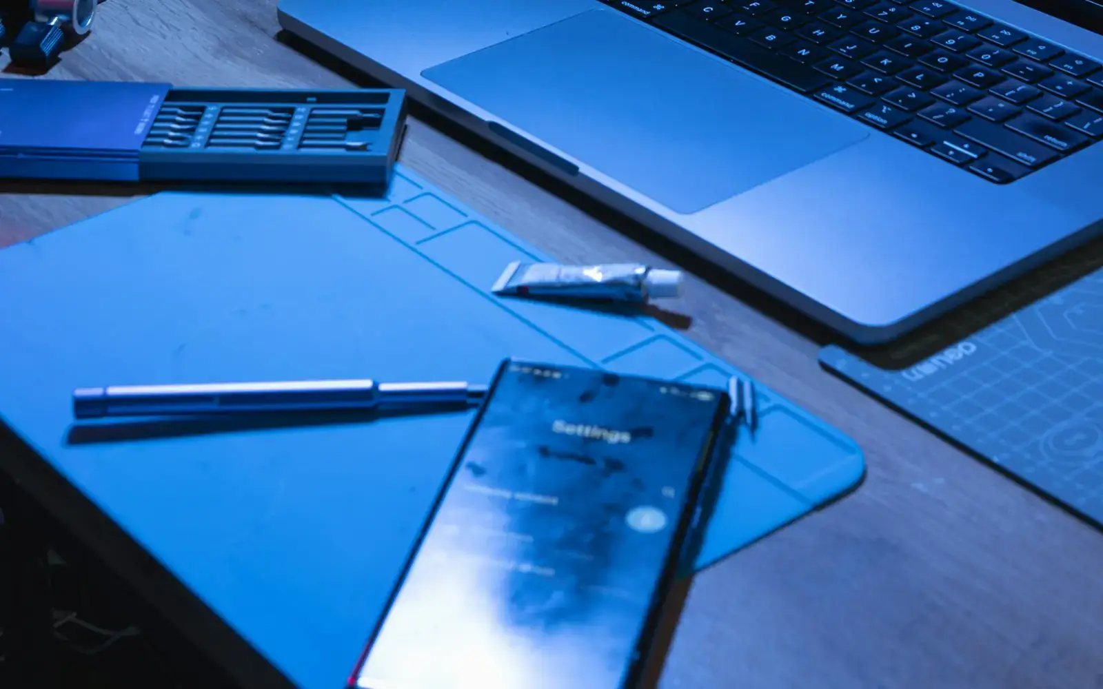 A laptop and phone on a desk with application code open