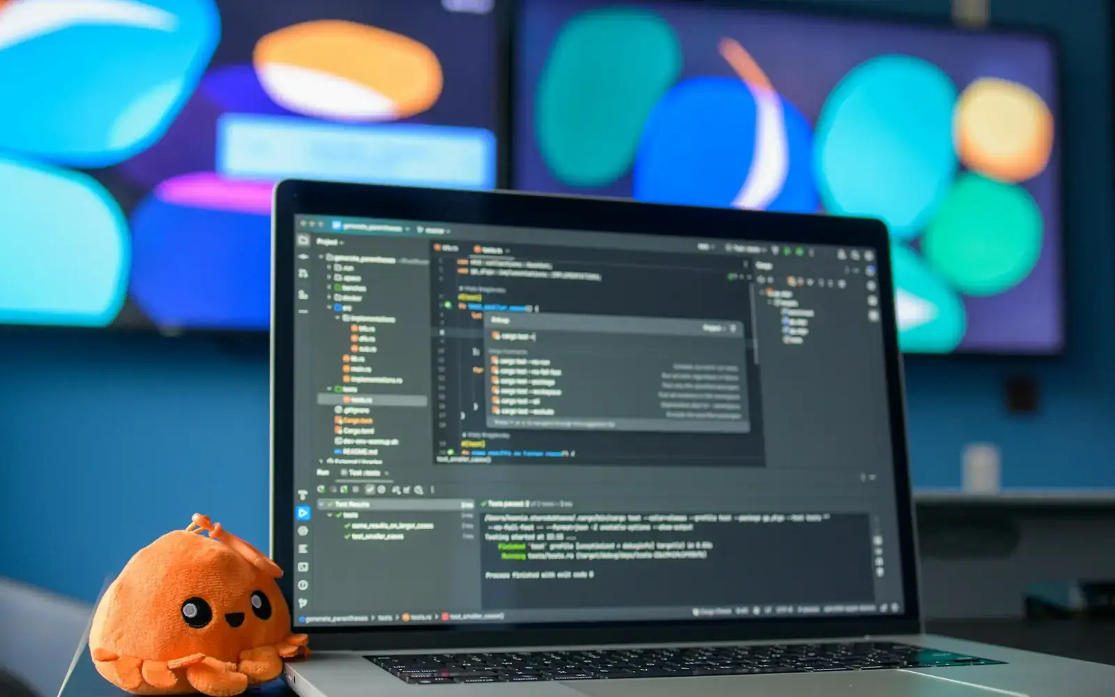 Laptop pengembangan aplikasi dengan hiasan gurita kecil di meja