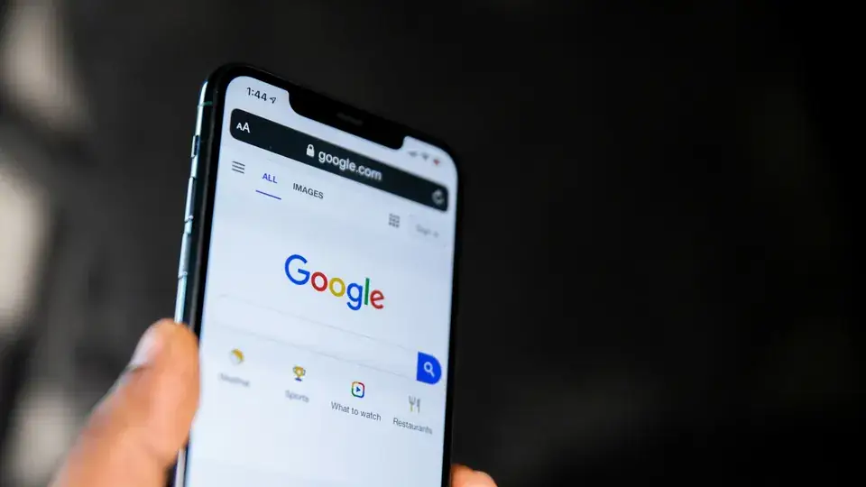 Hand holding mobile phone with Google search page